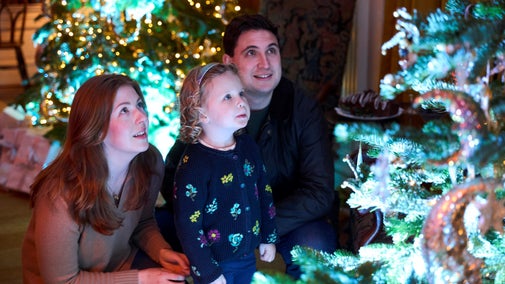 A mother and father and their young daughter admire a Christmas tree at Polesden Lacey